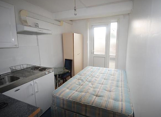 A bed in a kitchen, offered as a studio flat, in London