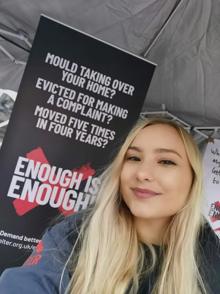 Shelter staff member standing in front of our sign that says Enough is Enough