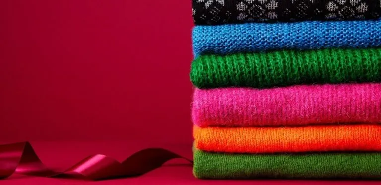 A pile of brightly coloured folded sweaters