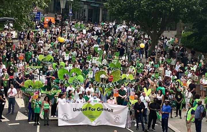 Campaigners marching, holding a 'United for Grenfell' banner