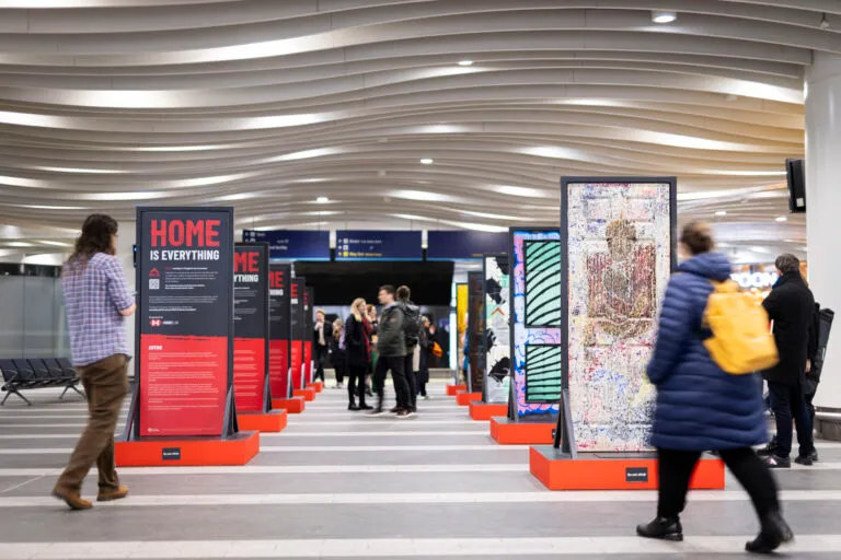 A collection of doors created by artists, located in Birmingham New Street Station with people rushing past.