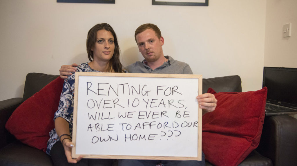 A couple holds up a sign asking for better protections for renters.