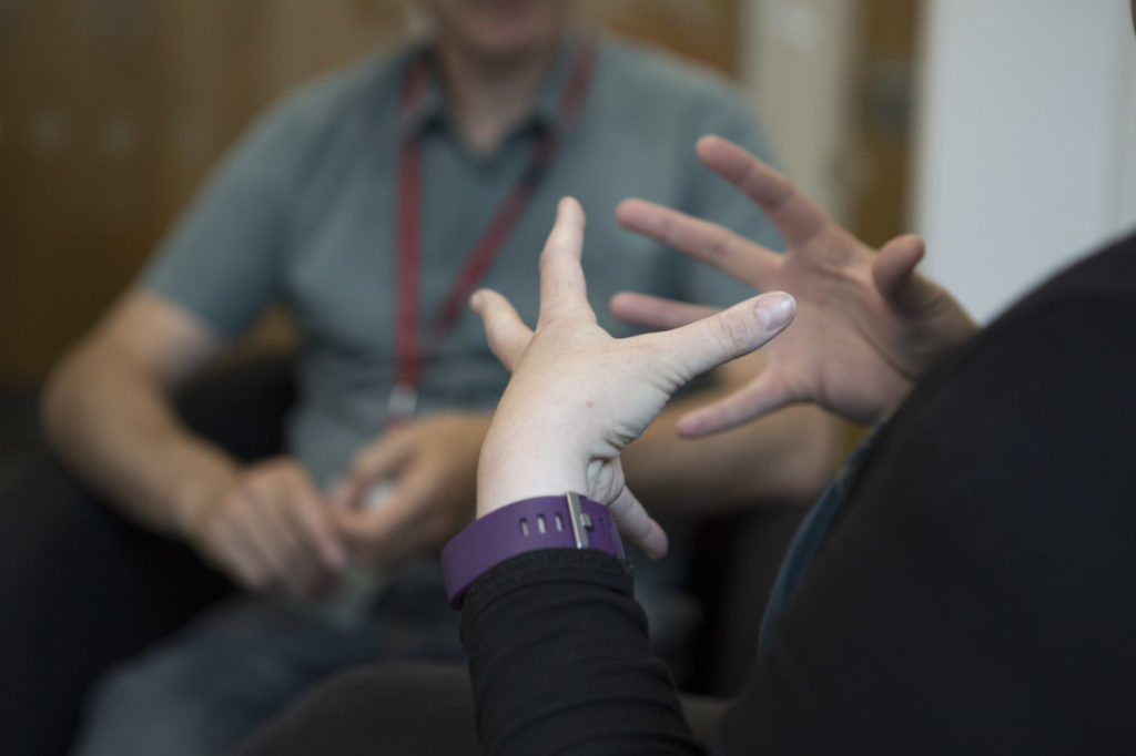A Shelter adviser in conversation with a Shelter client (played by Shelter staff) whose hands are in focus.