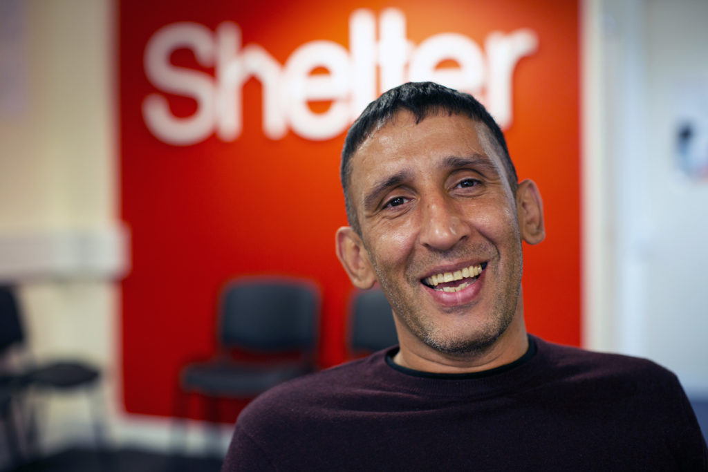 Paddy smiling in front of the Shelter logo