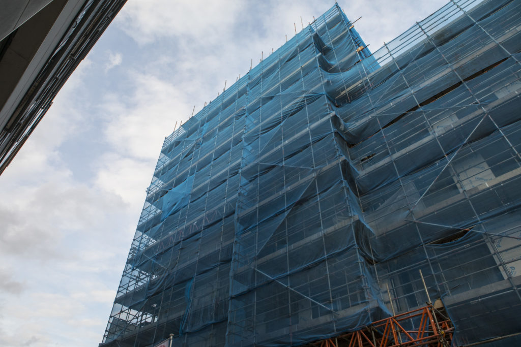 A photo of a high-rise building covered in scaffolding