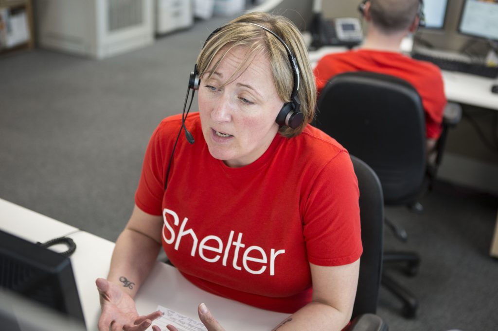 A female Shelter advisor sitting at a desk wearing a red Shelter t-shirt