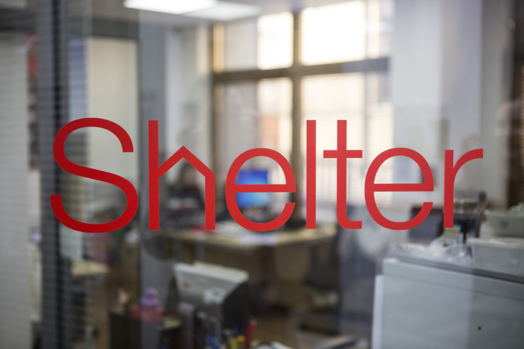 The Shelter logo on a window of a Shelter office, which is empty