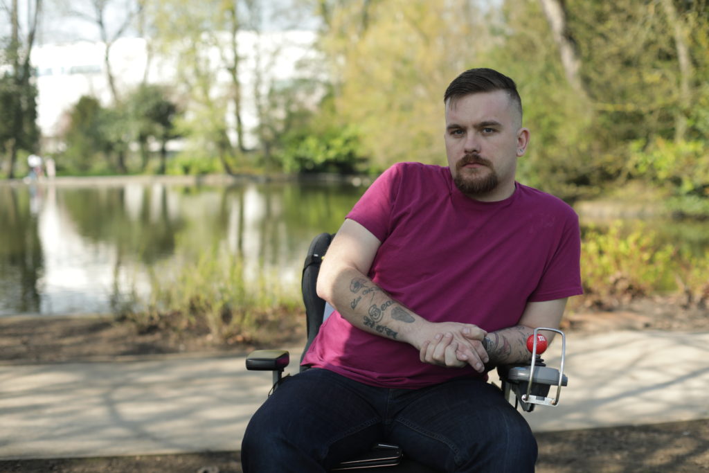 A man in a red t-shirt in a wheelchair in a park