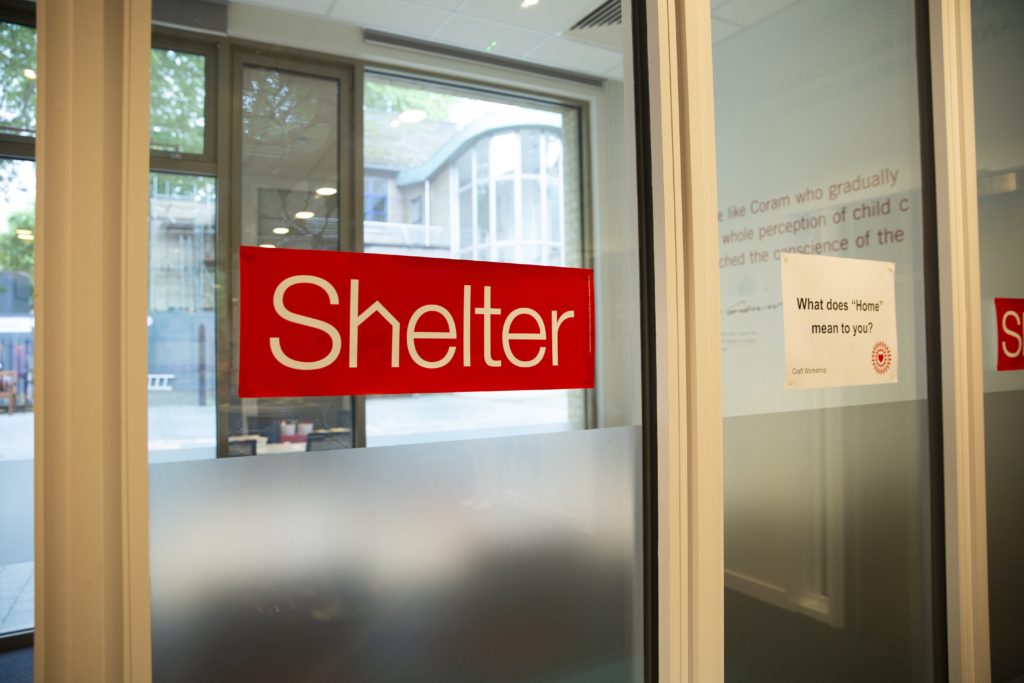 A sliding glass door at the entrance to a Shelter hub, which shows the Shelter logo