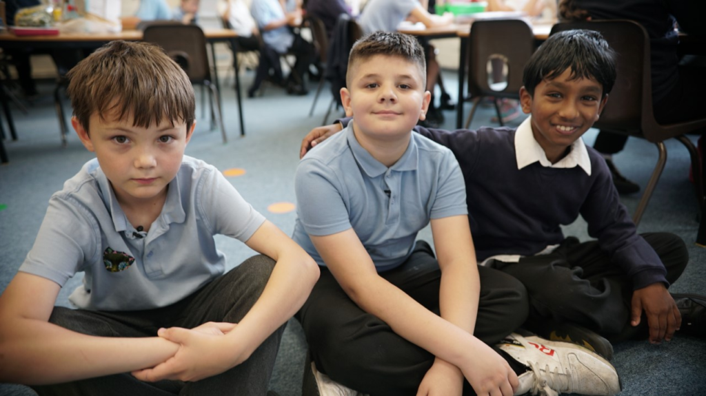 Three young boys sitting on the floor at school