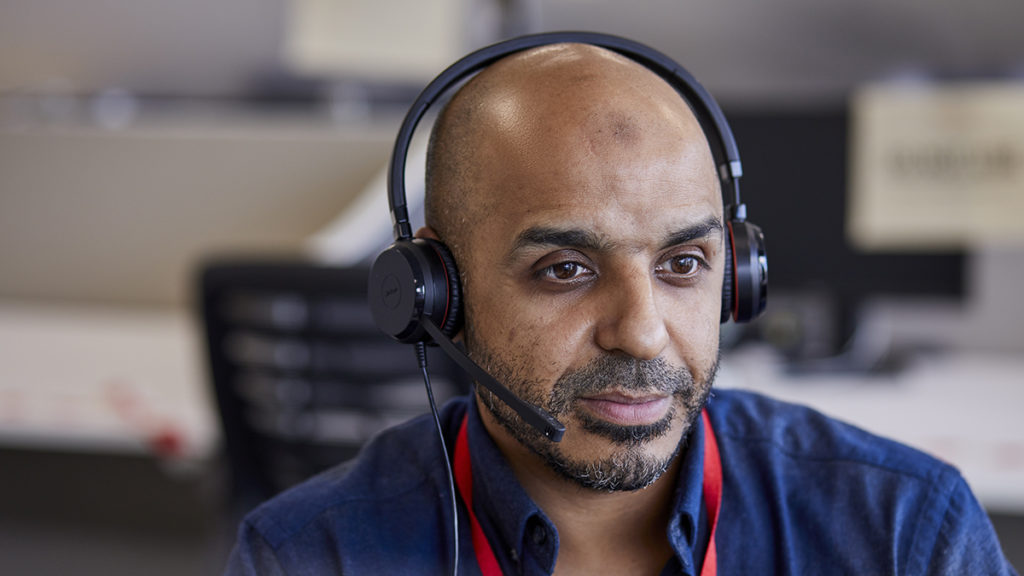 A helpline adviser wearing a headset sitting in an office