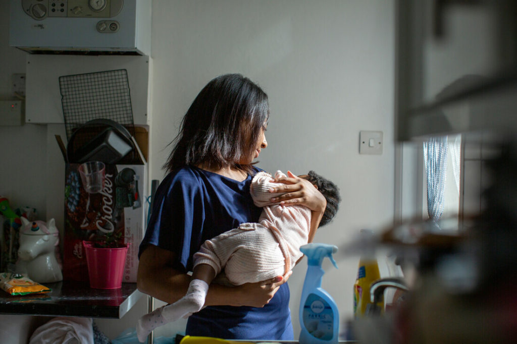A woman holds her baby in the kitchen