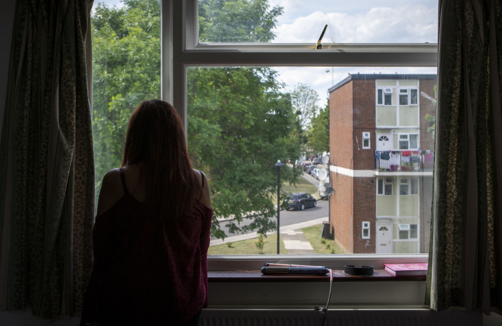 A woman looks out of a window from a block of flats
