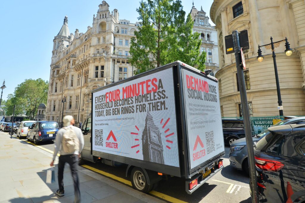 Shelter campaign advert on the side of a parked lorry. 'Every 4 minutes a household becomes homeless. Today Big Ben rings for them'.
