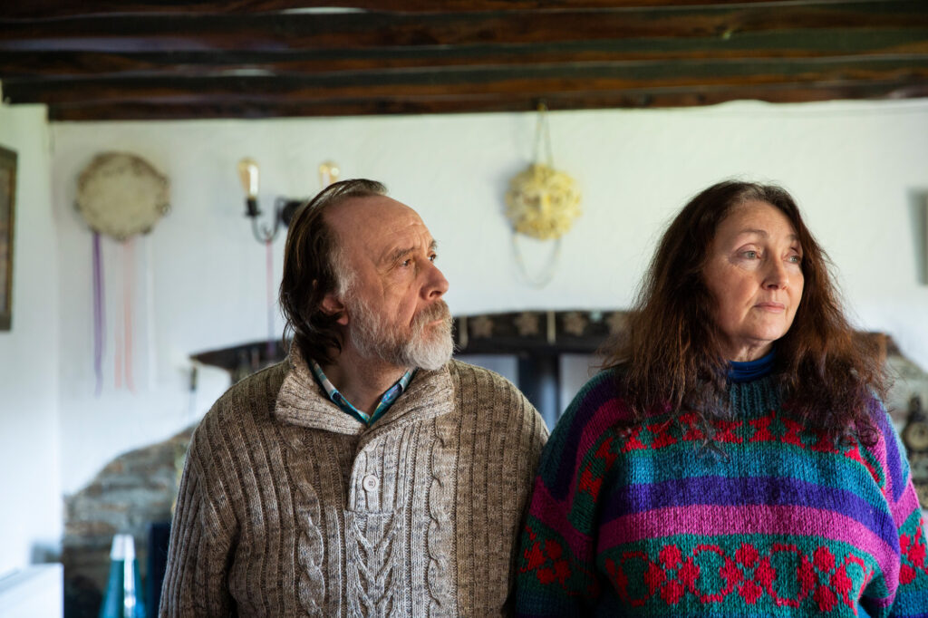 An older man and woman standing side by side in their home.
