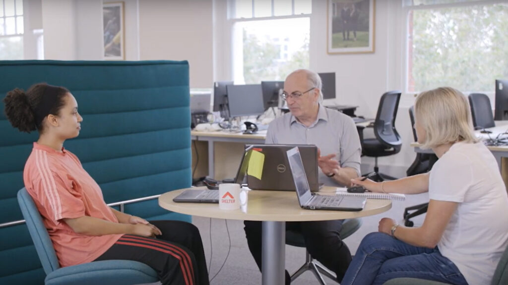 Colleagues sit around a table having a discussion in Shelter's London office